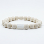 Pulsera blanca brillante de material cerámico con una piedra luna (moonstone) incrustada en el centro.