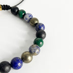 Acercamiento a las texturas de la piedra malaquita verde, roca volcánica negra y jaspe azul en pulsera masculina.