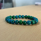 Manilla crisocola sobre mesa de madera, piedra natural