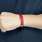 Persona usando pulsera de cuero redondo color rojo con detalles de broche dorado