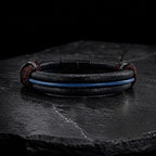 pulsera de cuero redondo color negro y tira de cuero central color azul, broches de acero