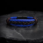Pulsera cuero trenzado color azul con broches de acero color negro, fondo oscuro