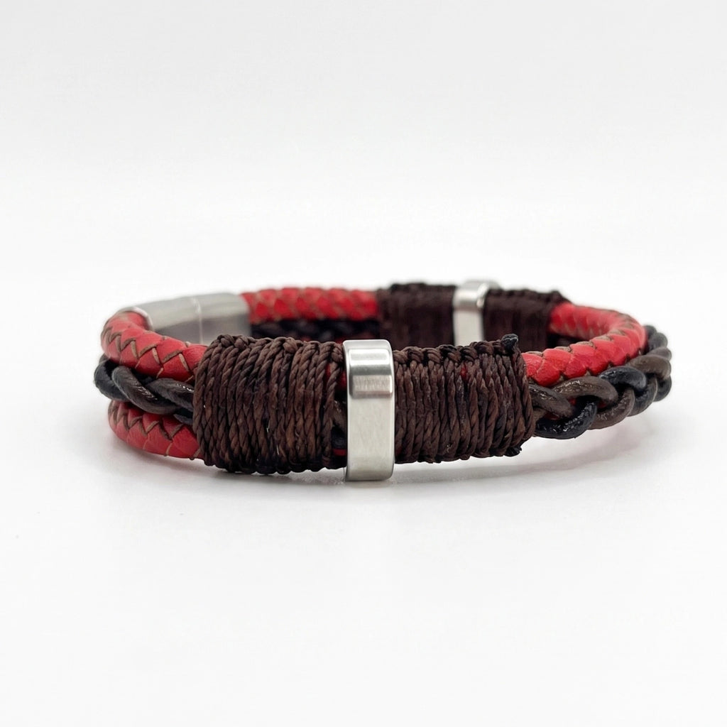 Detalle lateral de pulsera Desmos roja en cuero natural, resaltando el ensamble manual con hilo encerado oscuro y un separador central de acero inoxidable plateado.