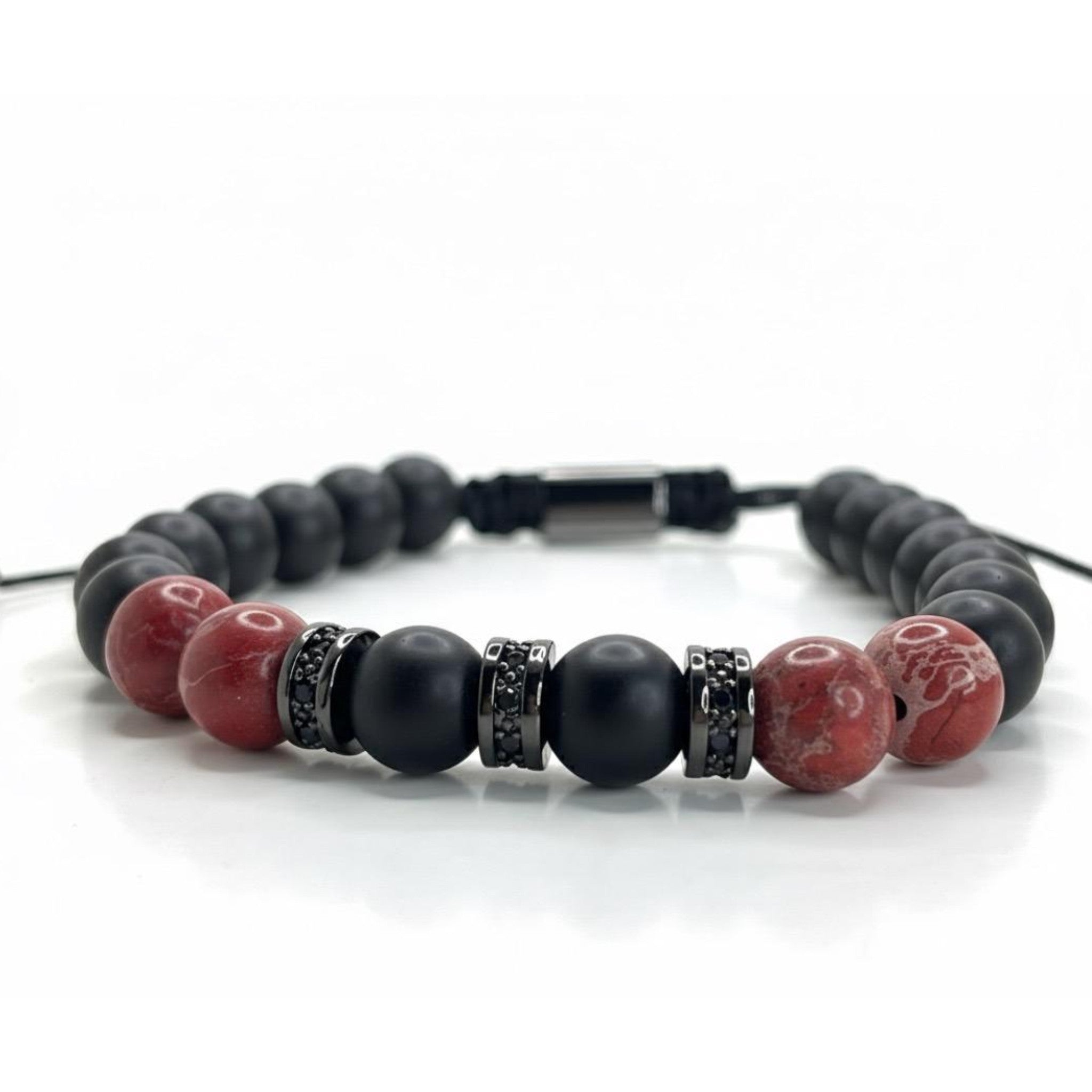 Pulsera ajustable Fuego Carmesí está diseñada con cuentas Onix-Mate y piedras Jaspe Rojo separadas entre sí por incrustaciones de circonita. 