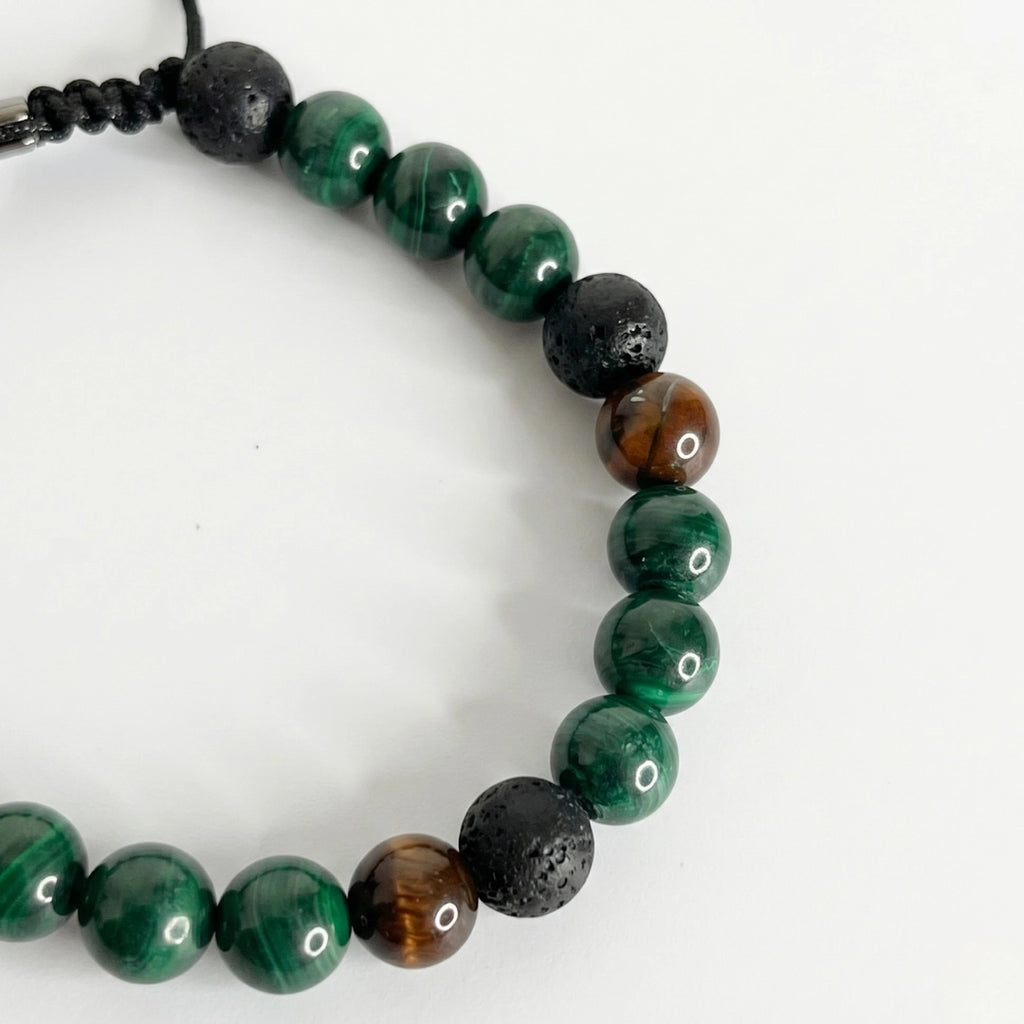 Detalle de pulsera de malaquita para hombre combinada con texturas terrosas y nudo corredizo ajustable.