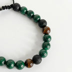 Detalle de pulsera de malaquita para hombre combinada con texturas terrosas y nudo corredizo ajustable.