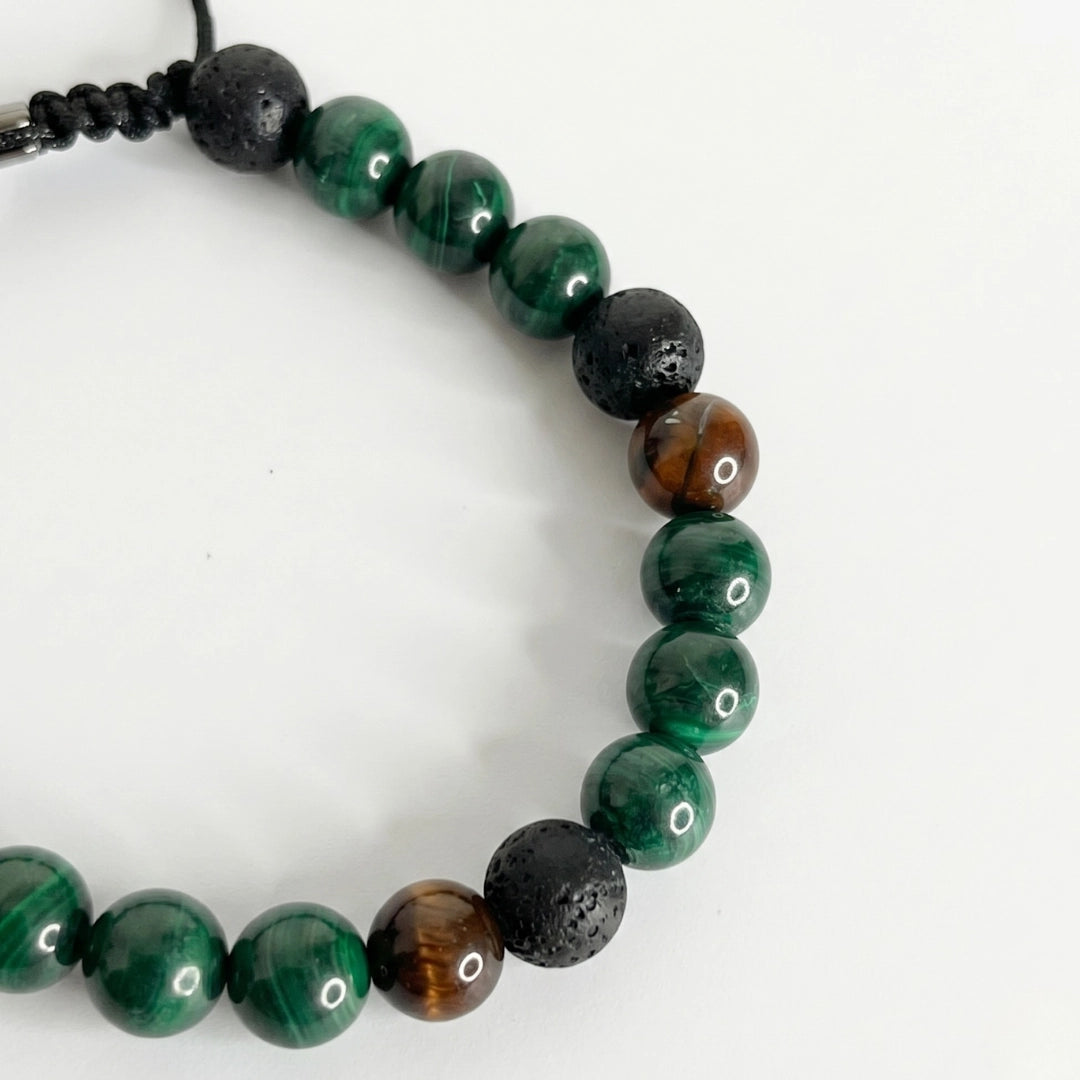 Detalle de pulsera de malaquita para hombre combinada con texturas terrosas y nudo corredizo ajustable.