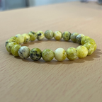 Pulsera o manilla serpentina sobre mesa de madera, accesorio para hombre, krv colombia