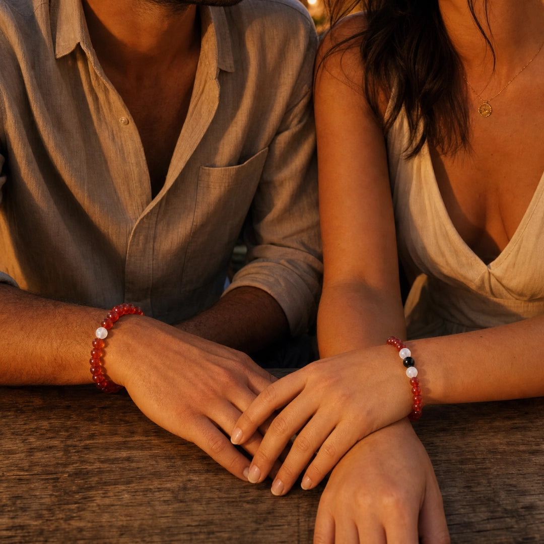 Pareja luciendo pulseras a juego de cornalina y jade blanco en las muñecas