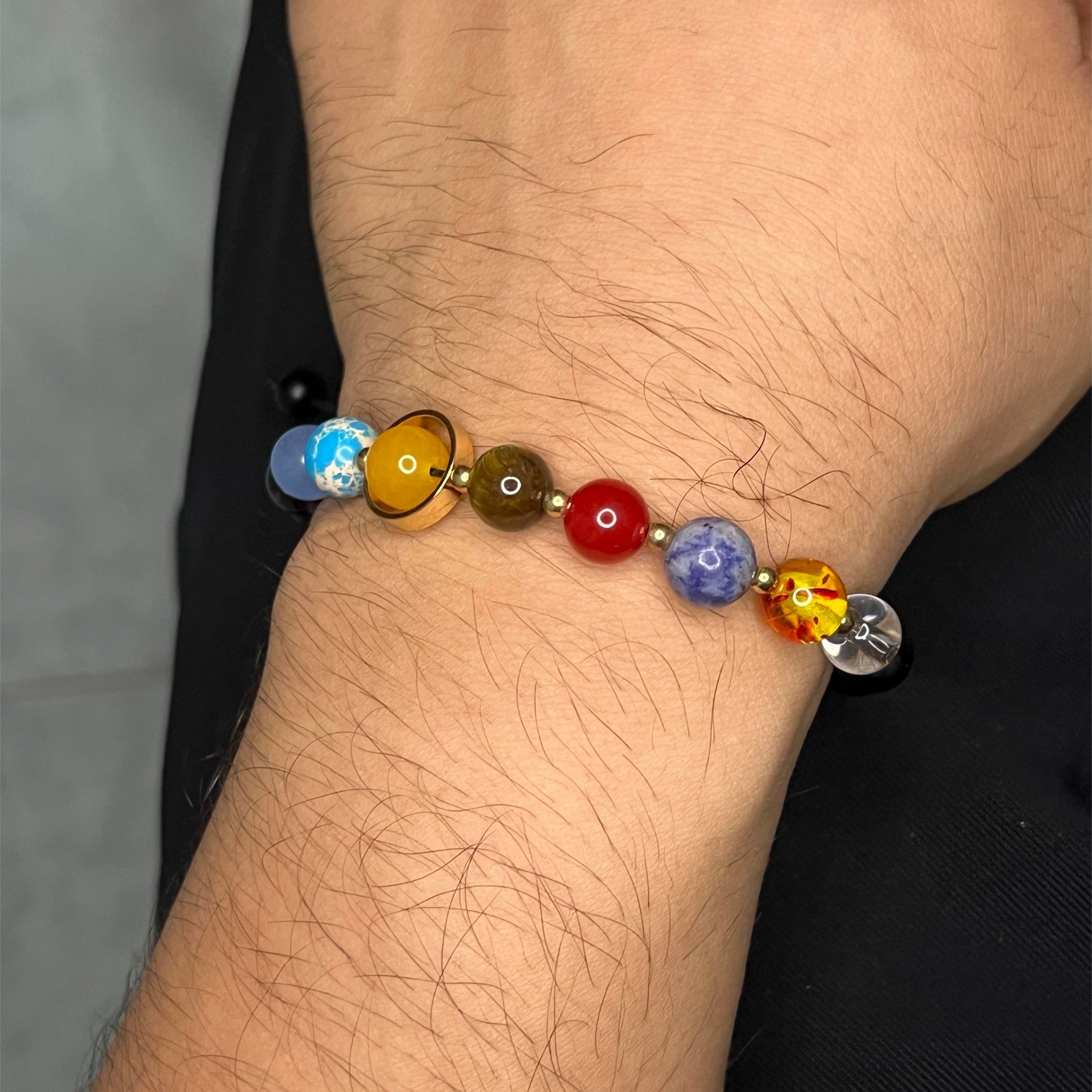 Esta pulsera única reúne las piedras naturales que representan a los 9 planetas del sistema solar, combinadas con cuentas de Ónix negro, símbolo de fuerza y protección
