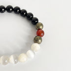 Detalle de pulsera con esferas de turmalina negra y selenita blanca unidas por nudo corredizo.