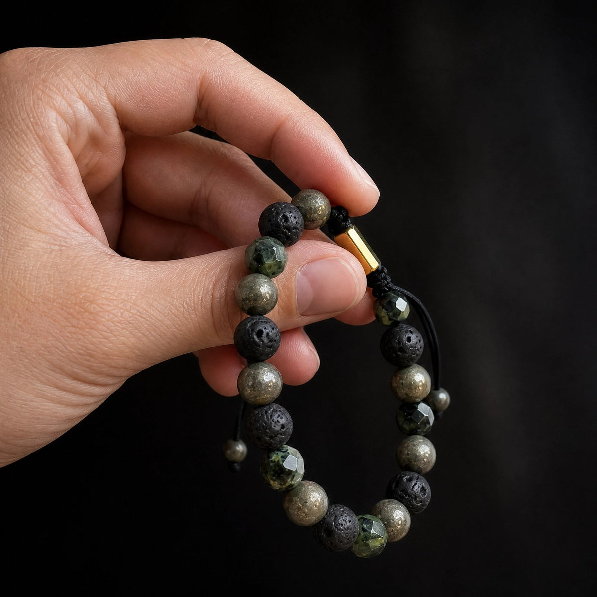 Pulsera de piedra pirita y jaspe kambaba sostenida, fondo negri minimalista